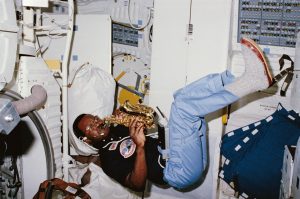 Astronaut floating in the space shuttle cabin playing a small saxophone